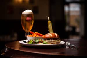 Beer, potato chips, salad and a burger with a pickle