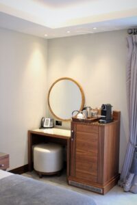 Small desk, mini fridge, mirror and an expresso machine