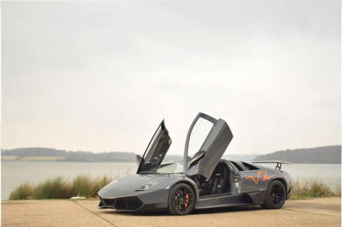 Lamborghini parked next to a lake with its doors lifted