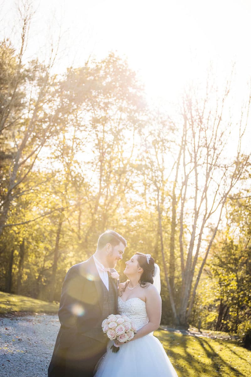 Couple looking at each other with sunshine and forest in the background