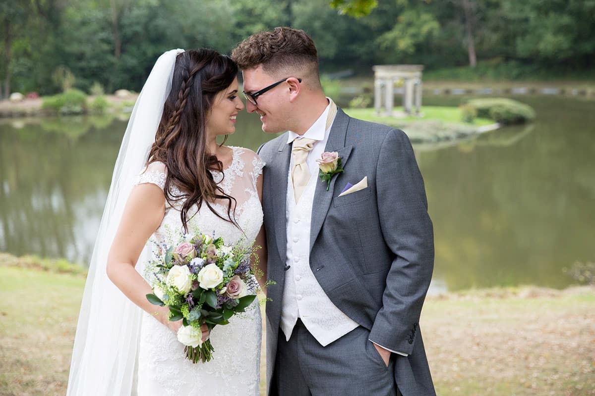 Recently Wedded Couple looking into each others eyes in front of a pond