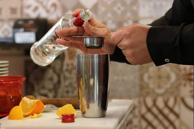 Person pouring vodka in a cocktail mixer