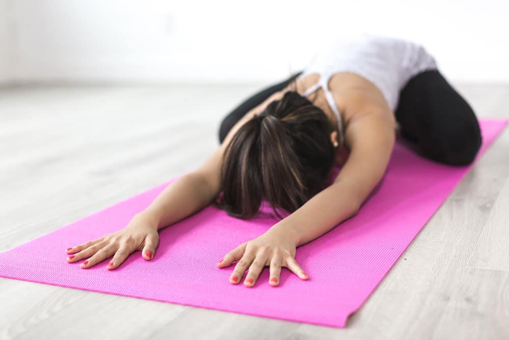 Woman doing yoga on a pink mat