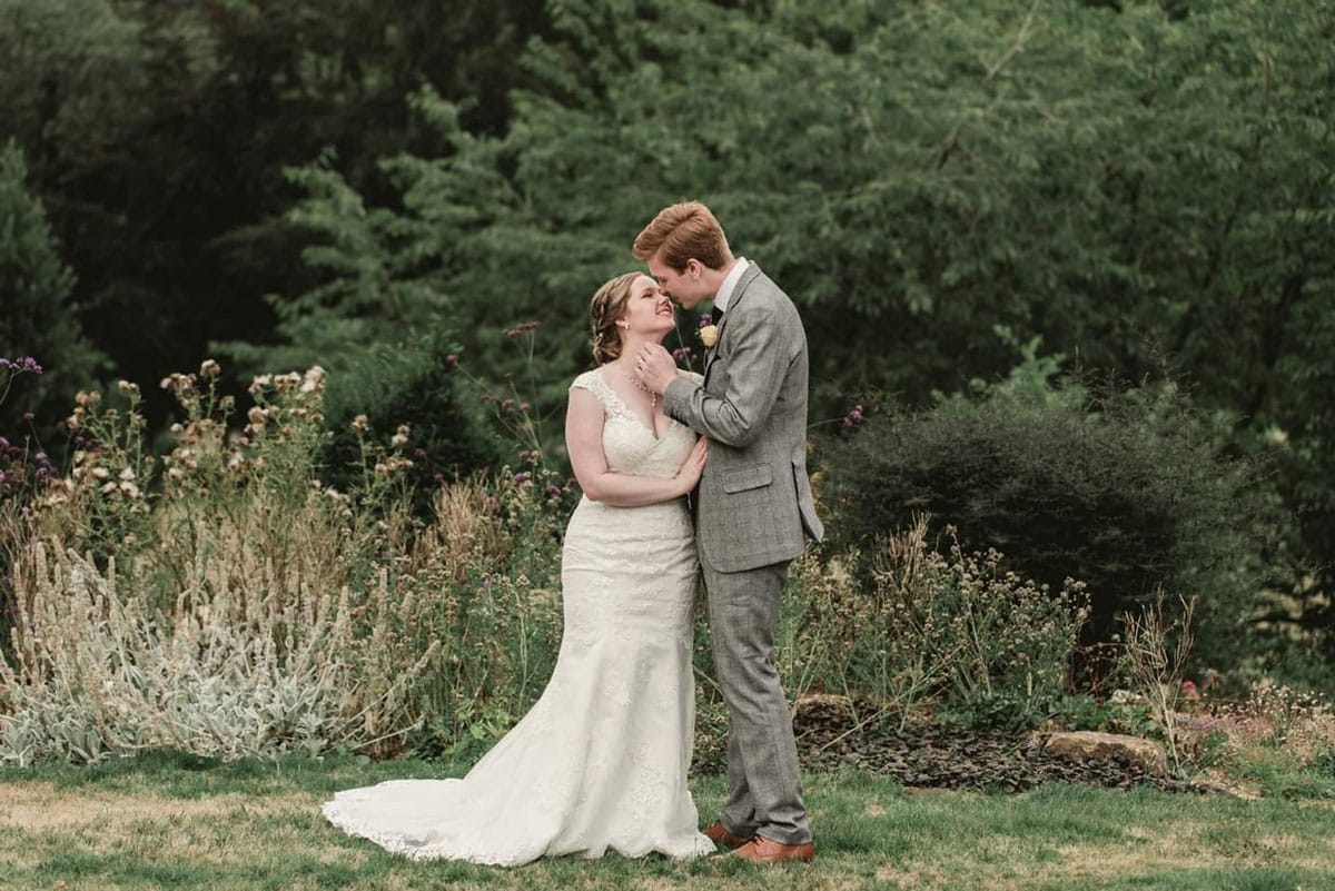 Couple about to kiss in front of bushes and trees