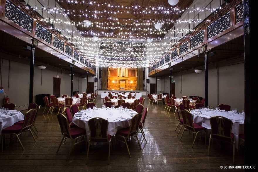 Event area with hanging shiny lights and tables with red chairs