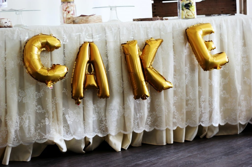 Balloons spelling "Cake" hanging in front of a table