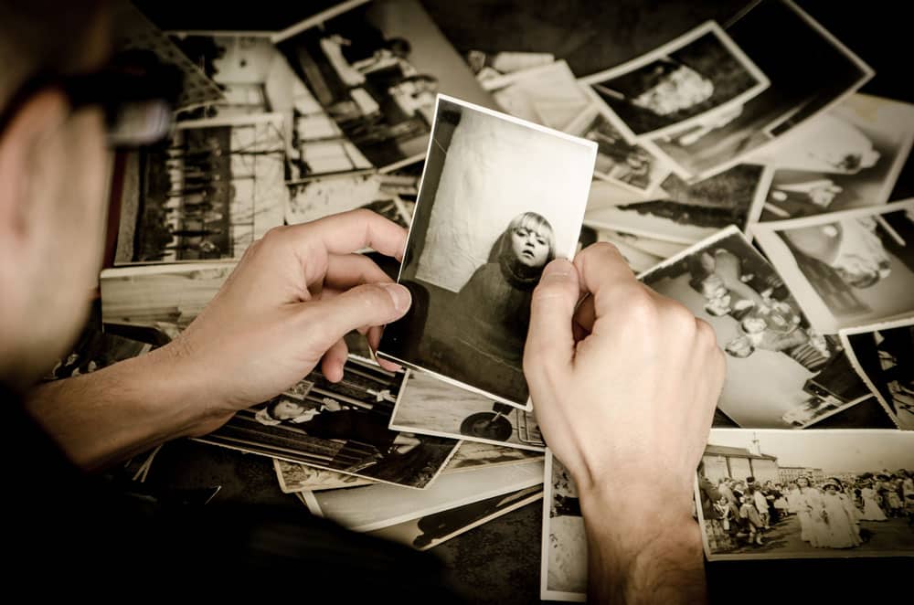 Person holding a black and white image of a kid with other black and white images spread on a table
