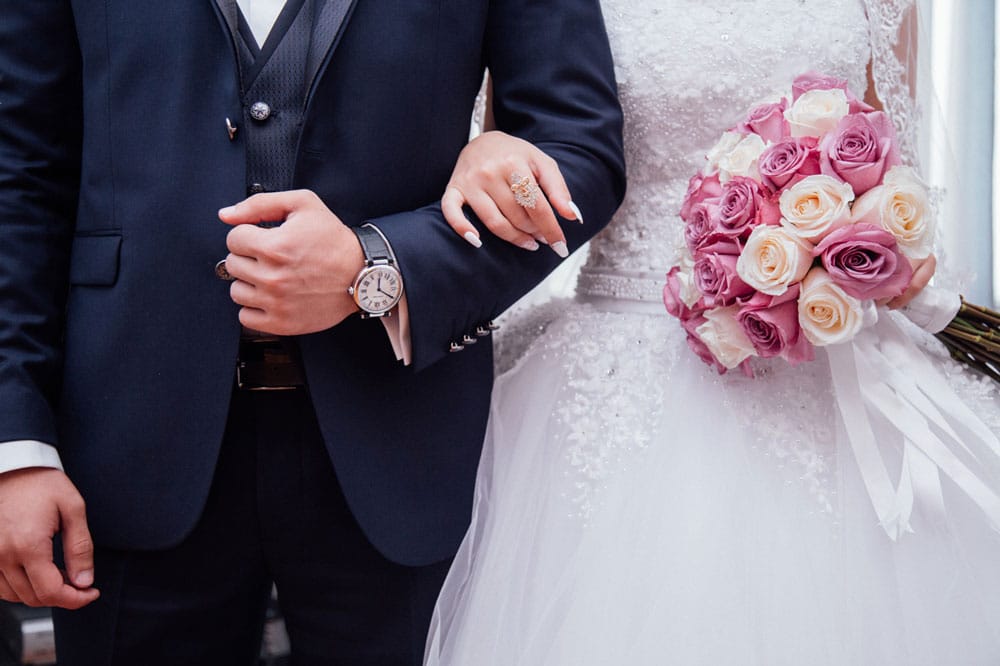 Man and woman in wedding clothing with arms intertwined