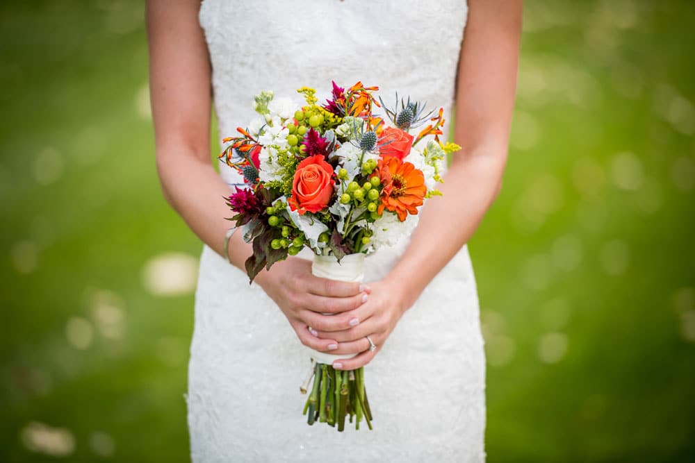 Woman in a white dress holding a bouquet of colourful flowers