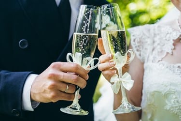 Bride and groom holding champagne glasses with white bows