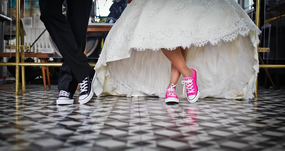 Two people in wedding dress and suit wearing converse shoes