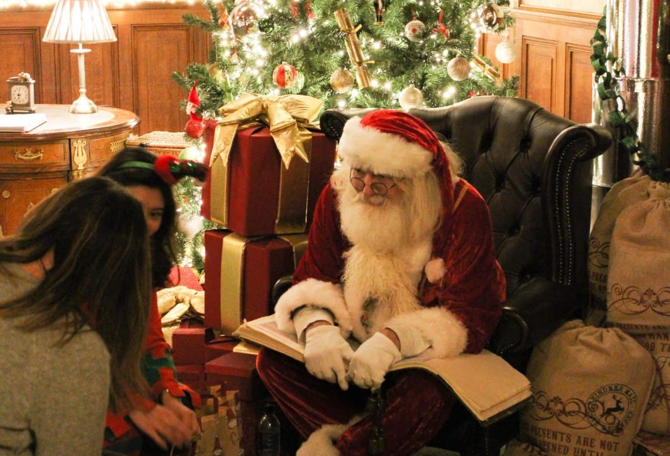 Santa Claus sitting on an armchair in front a of a Christmas tree