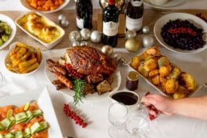 Christmas lunch table with roasted turkey, potatoes, Brussel sprouts, salmon and wines