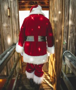Back of Father Christmas walking through wooden door