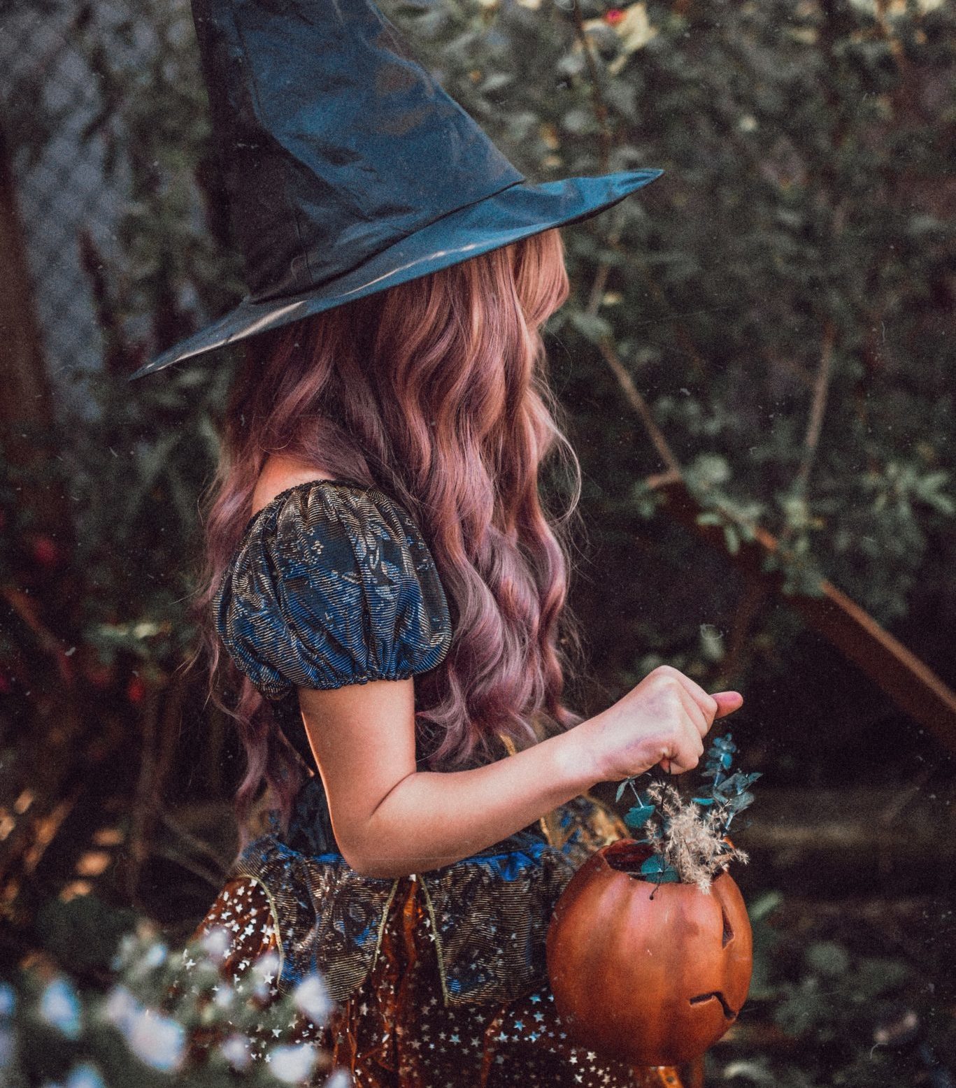 Person dressed up as a witch holding a pumpkin with flowers