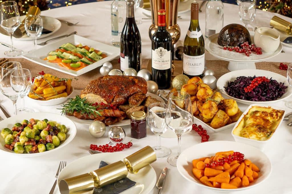 Christmas table spread with turkey, potatoes, vegetables, wine and Christmas crackers