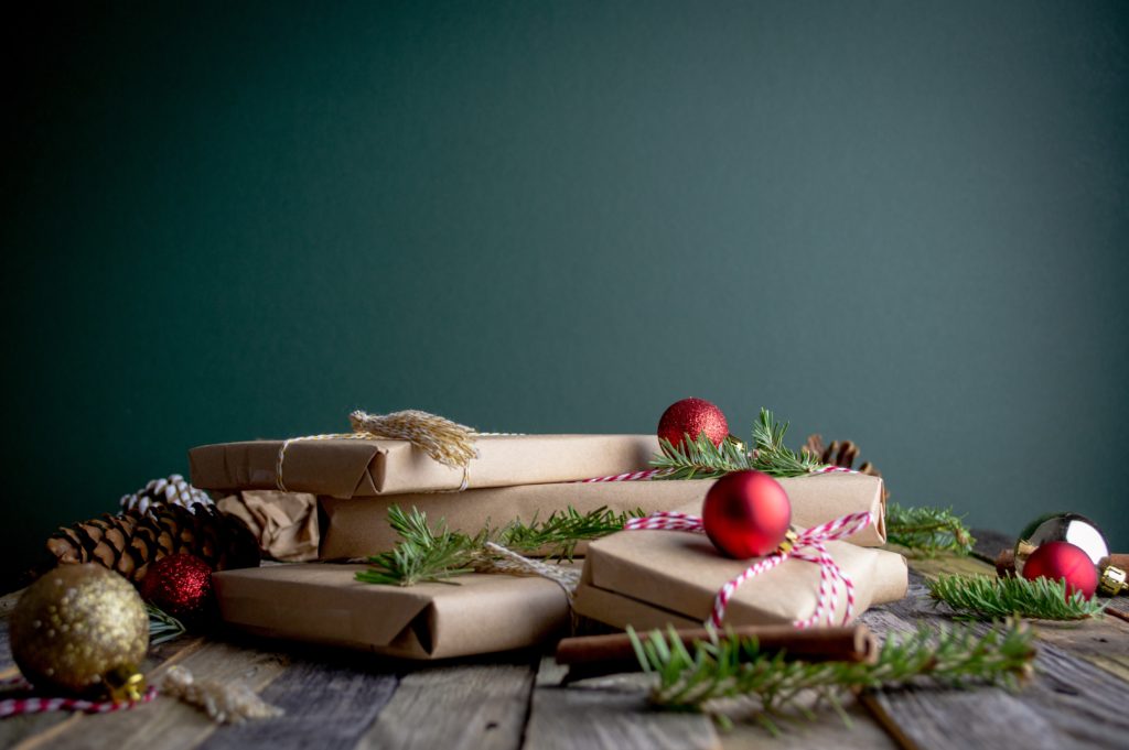 stack of presents in brown wrapping paper surrounded by tinsel and baubles