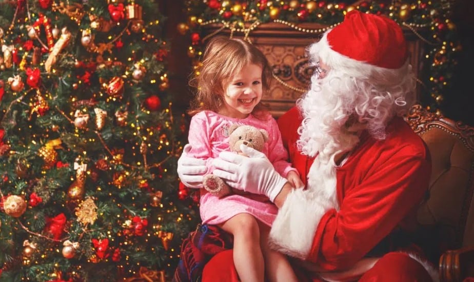 Santa with a girl and her teddy bear on his lap