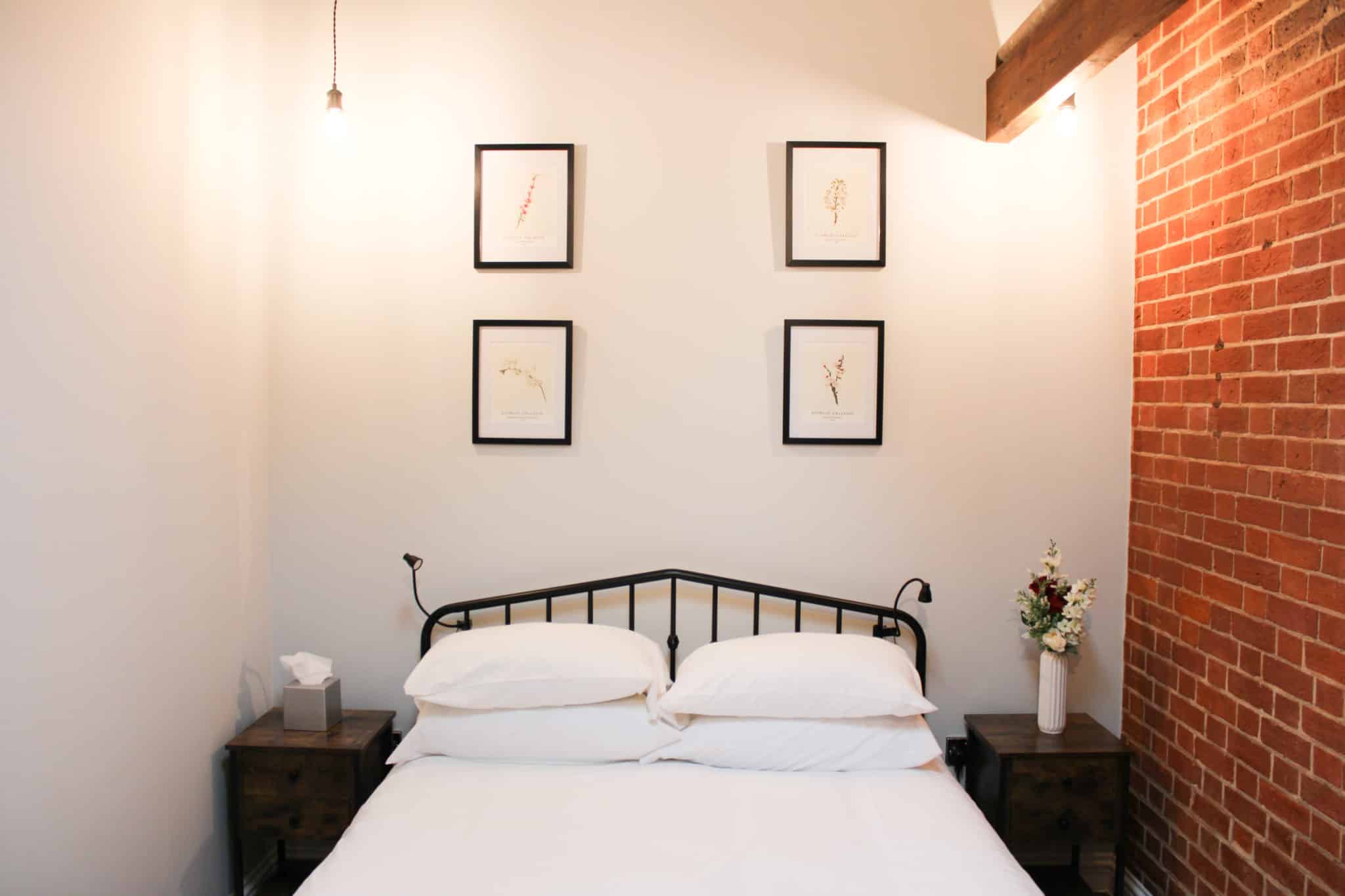 neatly furnished bedroom with a brick wall and wooden beam aesthetic
