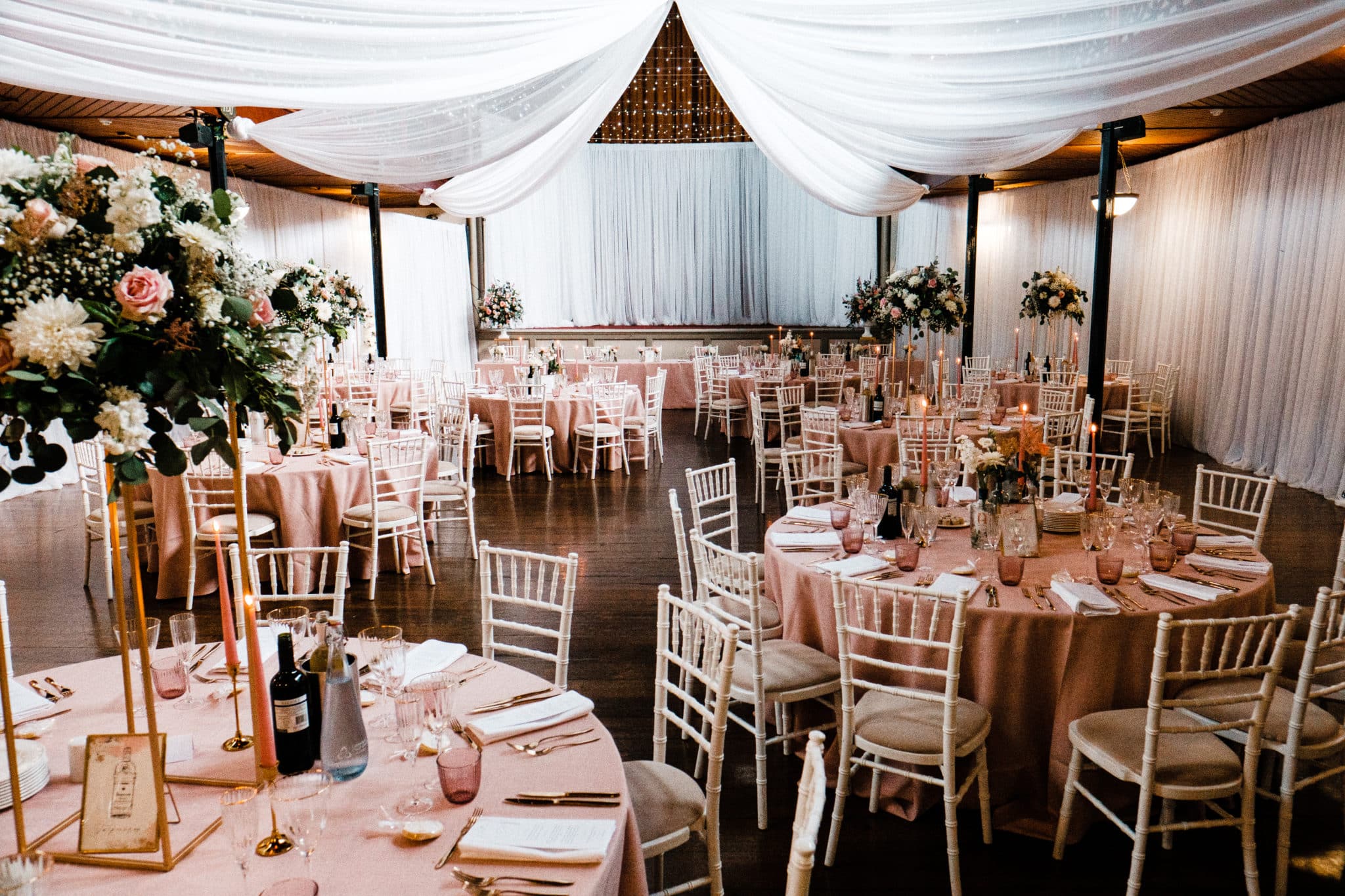 Pink themed wedding reception area with tables, chairs and flower bouquets