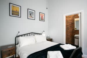 Bedroom with a double bed, decorated with 3 picture frames hanging above and a door to the bathroom