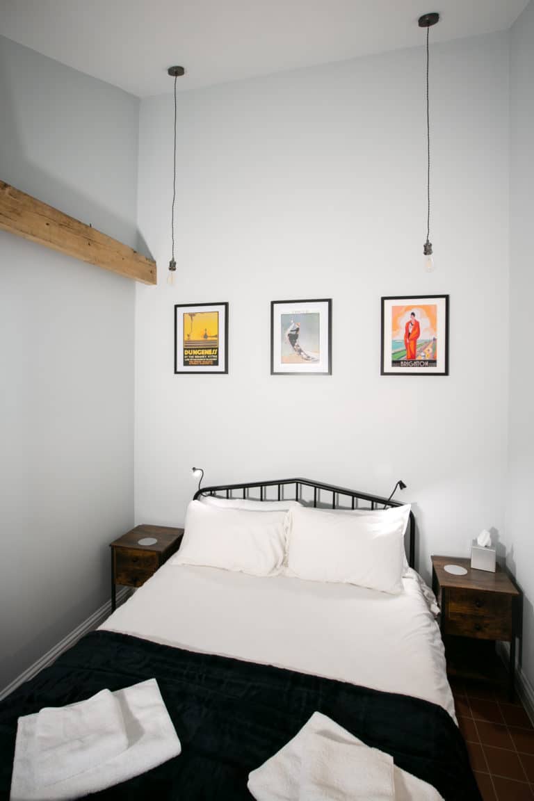 Bedroom with a double bed with 3 picture frames on the wall and two hanging lights