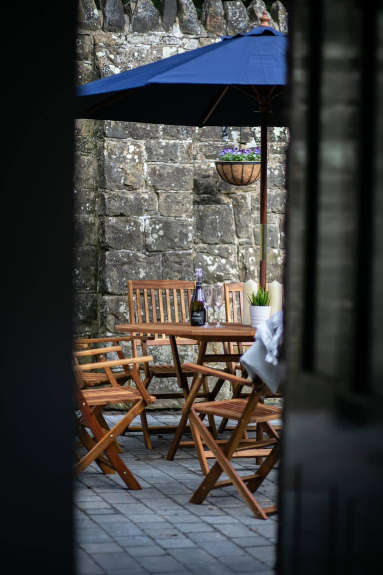 Outdoor area with wooden chair and table with champagne and two glasses