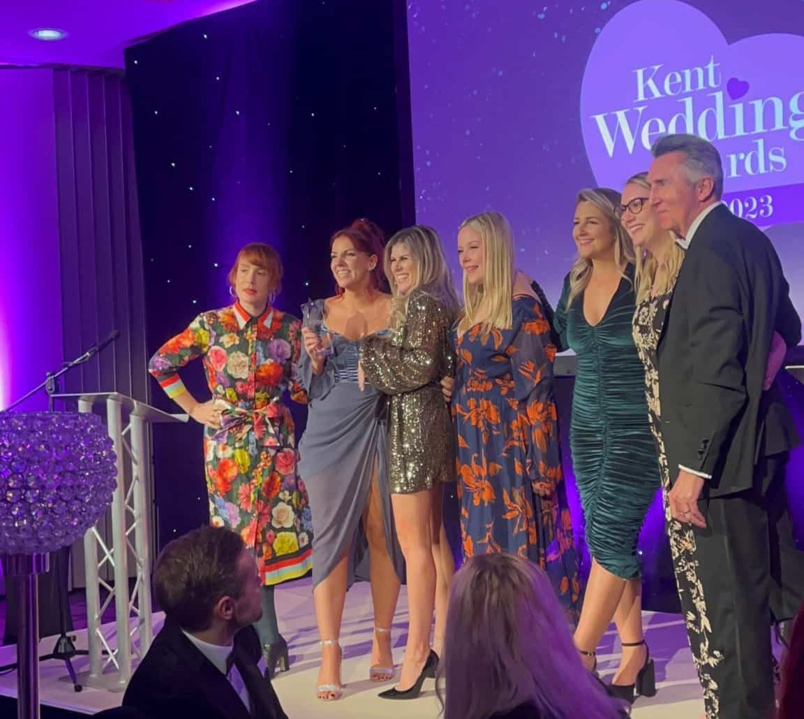 seven people posing for a picture on the stage of the 2023 Kent wedding awards