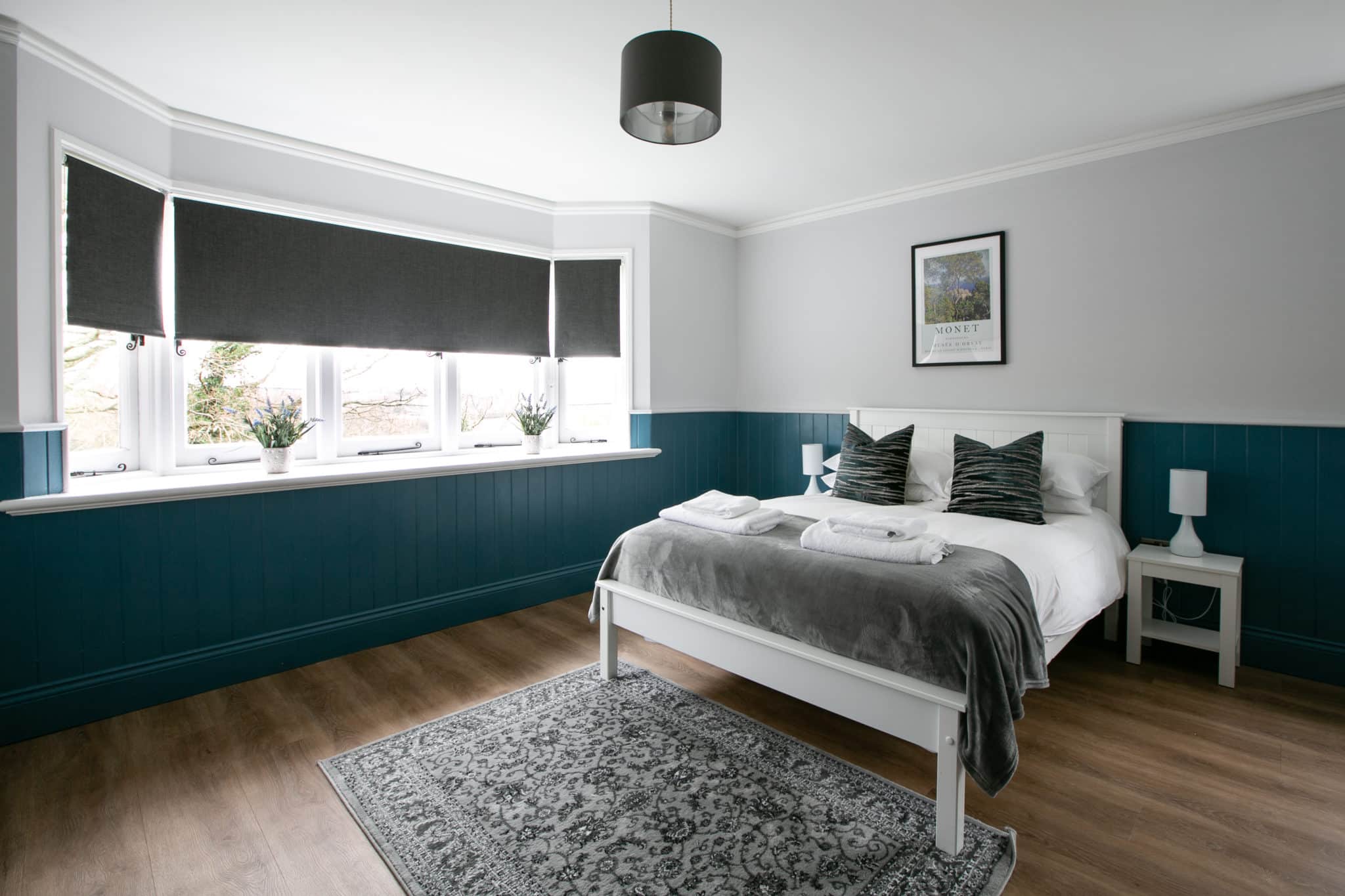 Grey and white themed bedroom with a double bed, nightstand and big window.